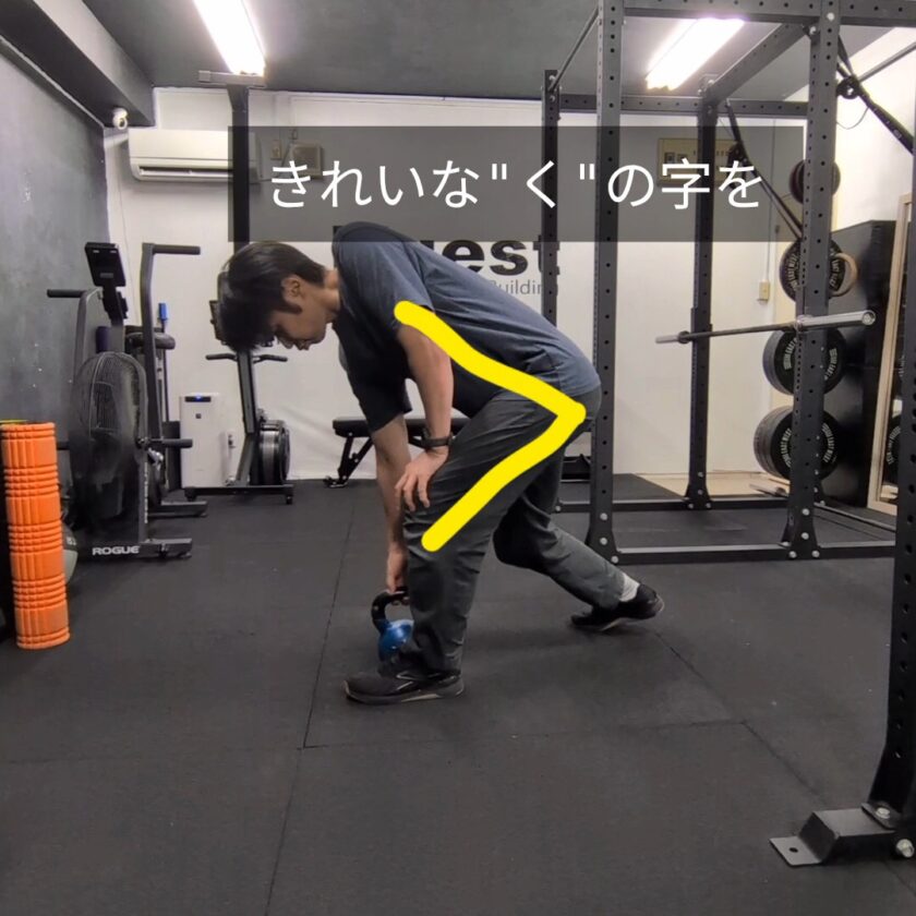 腰に負担をかけない「く」の字の前傾姿勢を解説するトレーナー