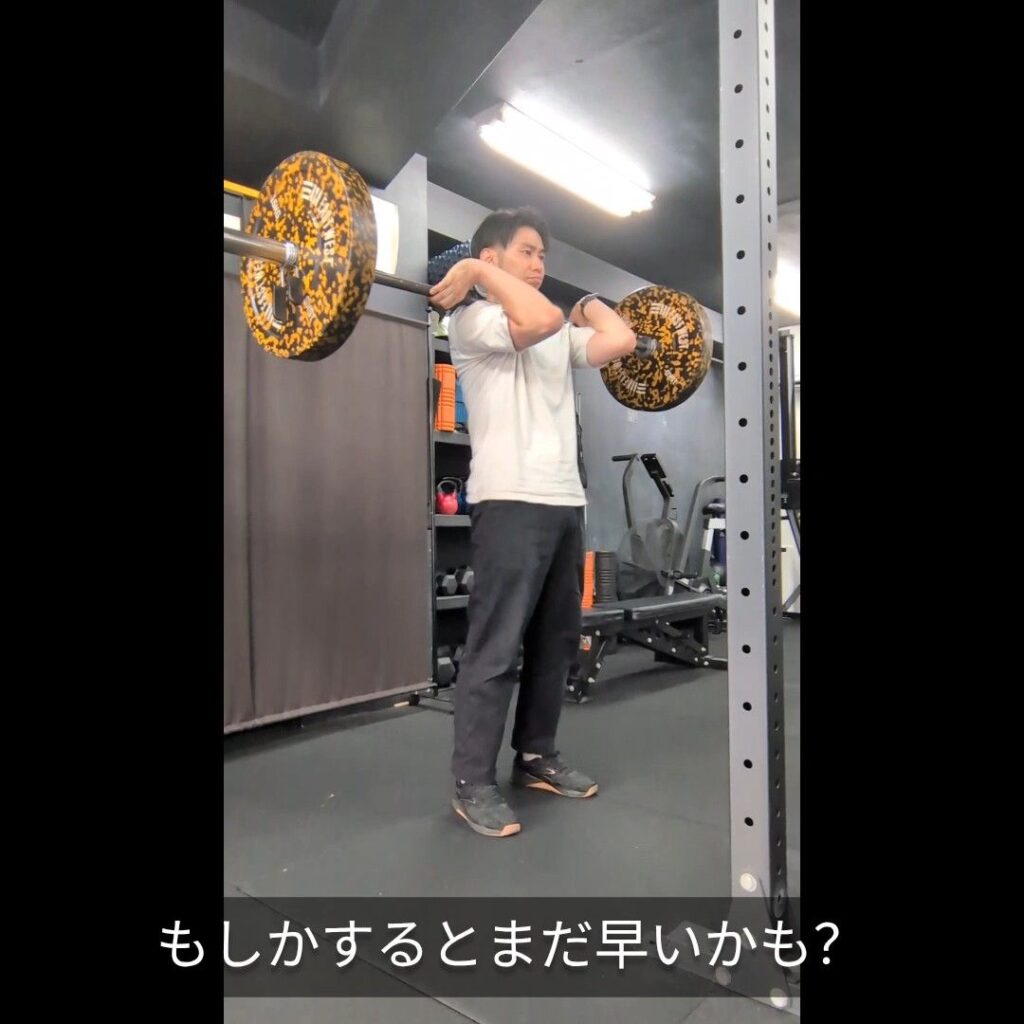 バーベルを肩に担いでトレーニングするトレーナー